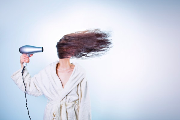 Woman blow-dry her hair in front of her face